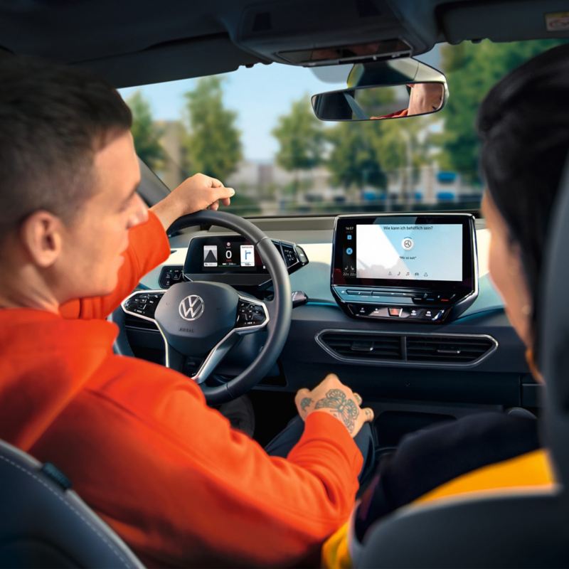 „VW ID.3“ vairuotojas naudoja valdymą balsu; prietaisų skydelio vaizdas, žvelgiant iš automobilio galo