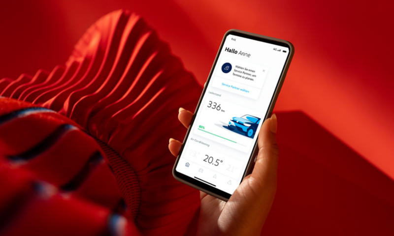 A hand holds a smartphone showing the VW We Connect ID. app. 