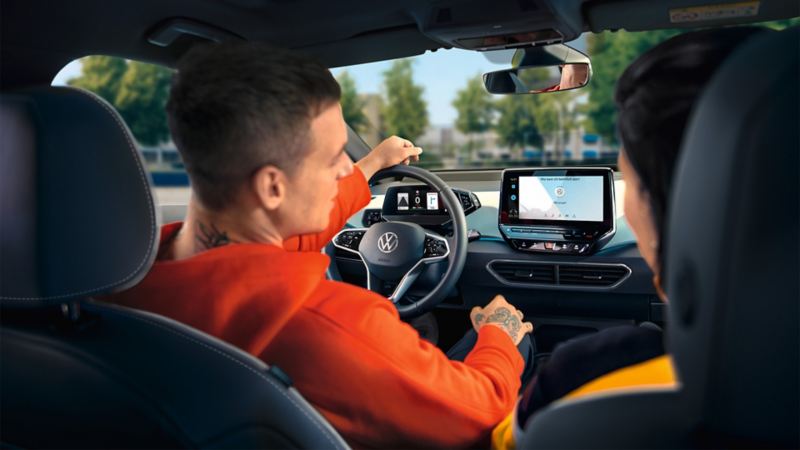 Fahrer nutzt Sprachbedienung im VW ID.3, Ansicht von hinten ins Cockpit