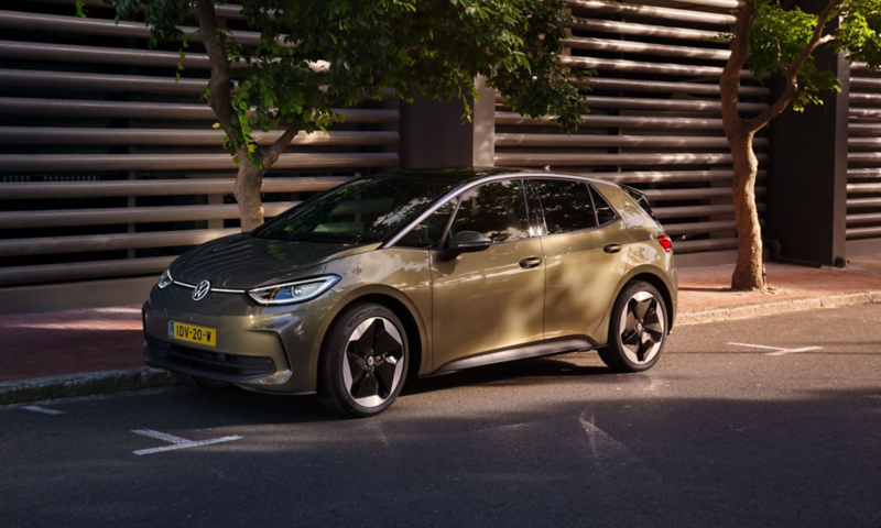 View of a VW ID.3 in “Dark Olivine Green Metallic” and “Sanya” wheel rims parked on the kerb at the side of the road. 