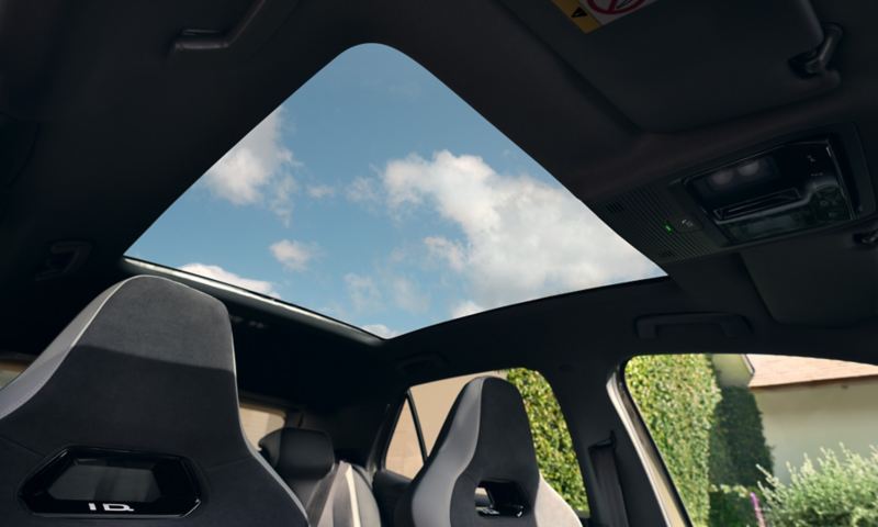 Vue en contre-plongée du toit vitré panoramique de la VW ID.3 avec une vue dégagée sur le ciel.