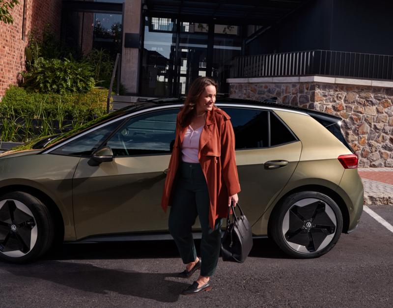 Vrouw loopt weg van een Volkswagen ID.3 die geparkeerd staat voor een gebouw