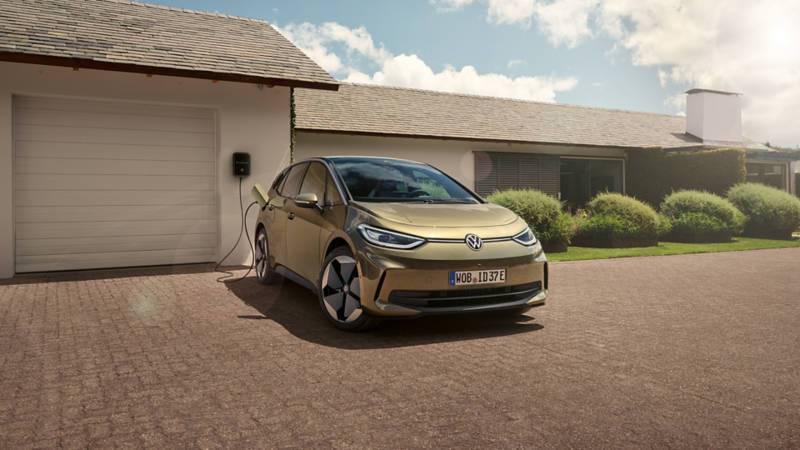 Blick auf einen VW ID.3, der vor einer Garage parkt und an eine Ladestation angeschlossen ist.