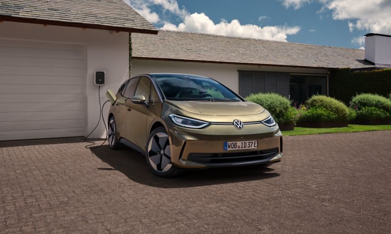 A view of a VW ID.3 parked in front of a garage and connected to a charging station.