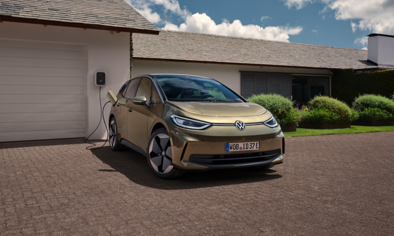 A view of a VW ID.3 parked in front of a garage and connected to a charging station.