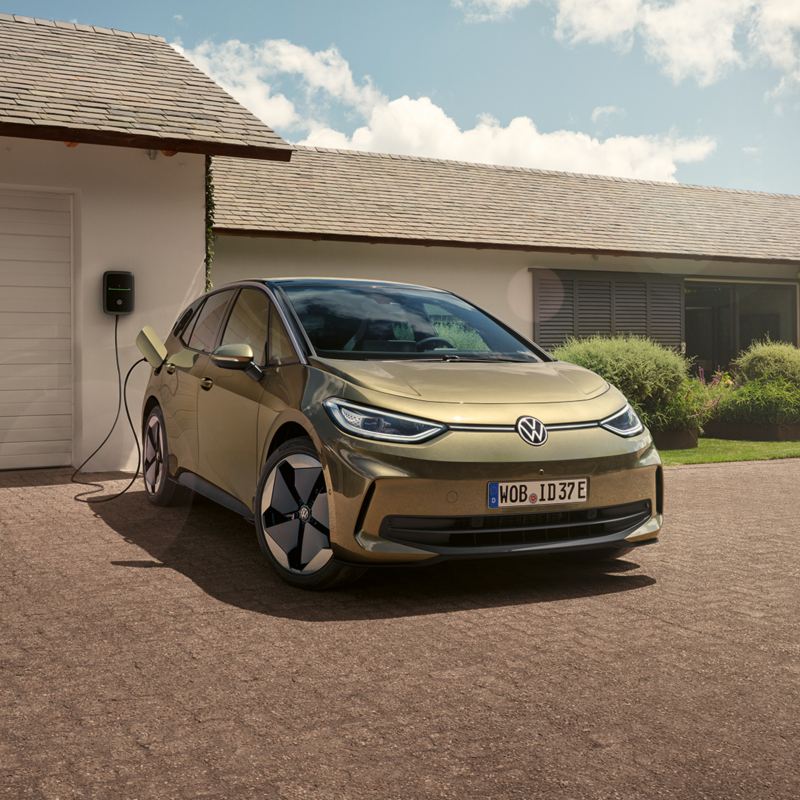 Blick auf einen VW ID.3, der vor einer Garage parkt und an eine Ladestation angeschlossen ist.