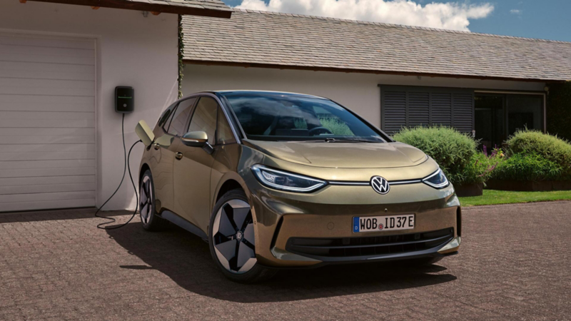 A view of a VW ID.3 parked in front of a garage and connected to a charging station.