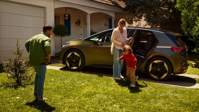 Mamma, papà e un bambino in giardino, accanto a una Volkswagen ID.