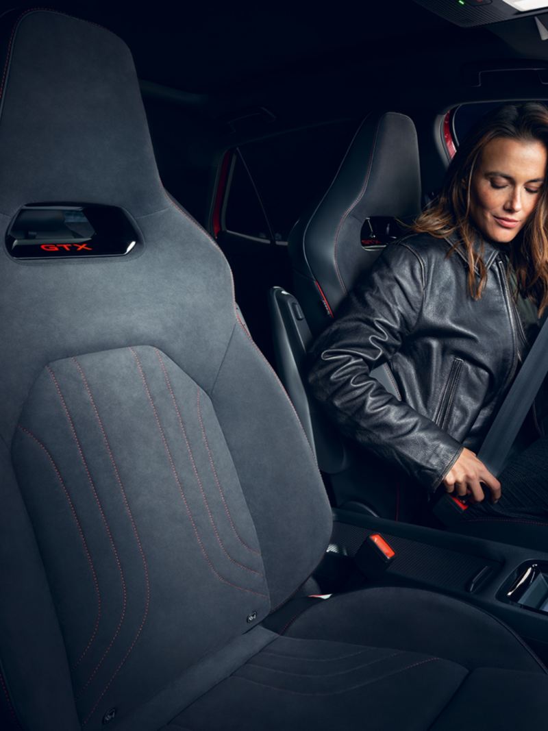 Vue intérieure de la VW ID.3 GTX avec une femme attachant sa ceinture sur le siège conducteur.