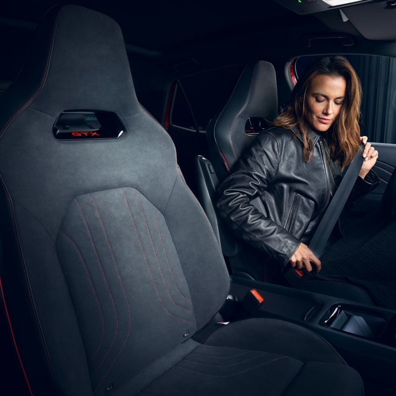 Vue intérieure de la VW ID.3 GTX avec une femme attachant sa ceinture sur le siège conducteur.