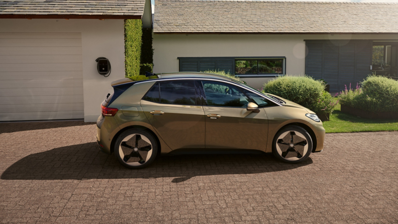 VW ID.3 stoi przed domem z garażem. Widok z boku.