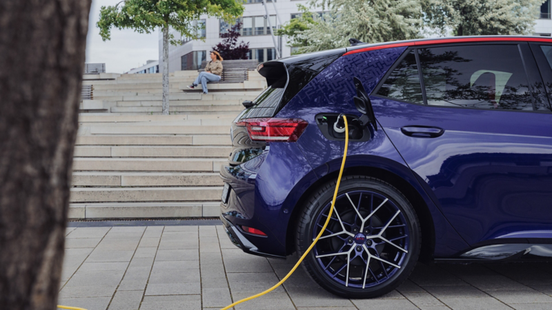 Een paarse VW ID.3 GTX FIRE+ICE staat geparkeerd in een stedelijk gebied en wordt opgeladen.