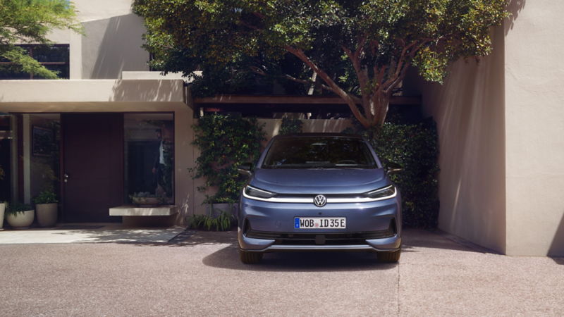 En blå vw id3 neo kompaktbil parkert utenfor et hus