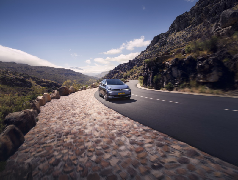 A blue VW ID.3 Neo is driving on a winding mountain road. 