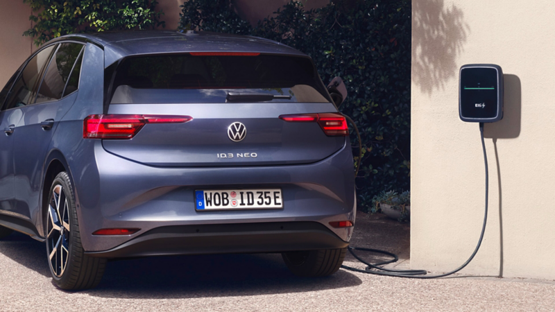 Ein blauer VW ID.3 Neo lädt an einer Wallbox vor einem Einfamilienhaus.