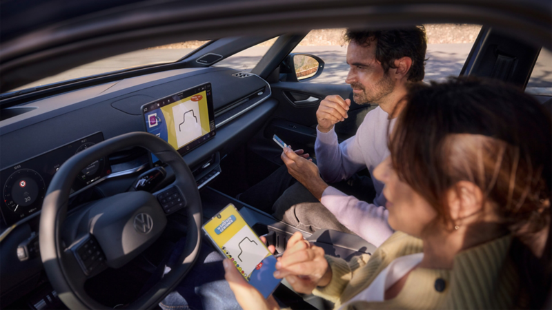Eine Frau und ein Mann spielen Pictionary auf dem Center-Display eins VW ID.3 Neo und nutzen ihre Smartphones als Controller