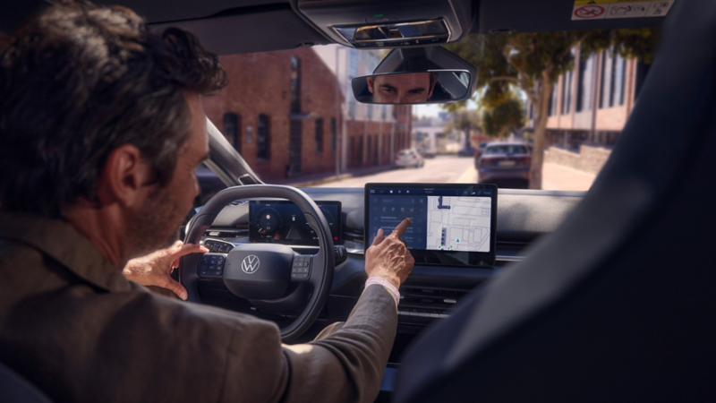 Ein Mann tippt auf die Zieleingabe im Navigationssystem eines VW ID.3 Neo.