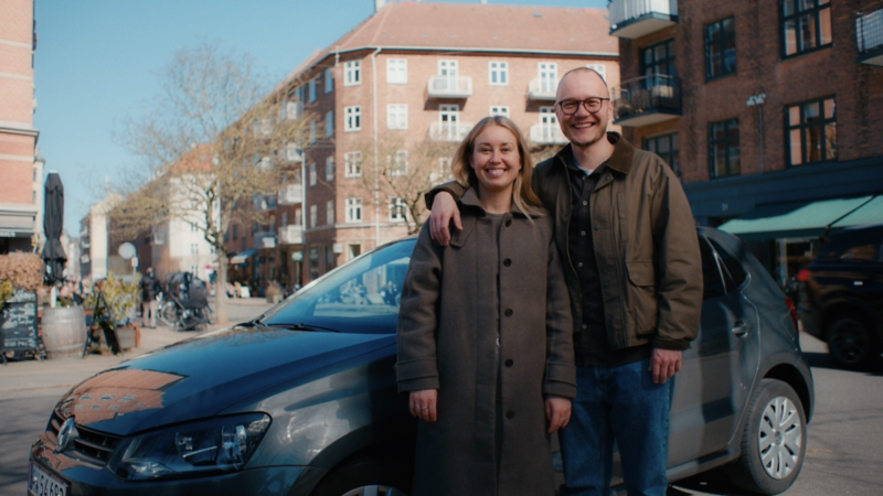 En mand og en kvinde står foran en polo midt i byen
