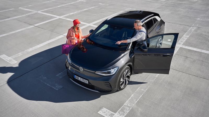 En VW servicemedarbejder viser en kunde noget på hendes elbil – VW service på elbiler