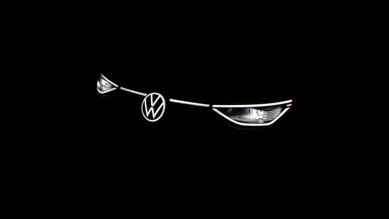 Vue avant de la ligne lumineuse éclairée et du logo sur un 2025 VW ID. Buzz dans un cadre sombre.