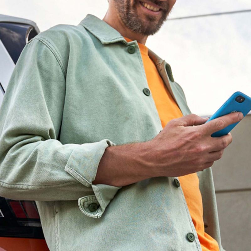 a man leaning against and ID. Buzz smiling at his phone