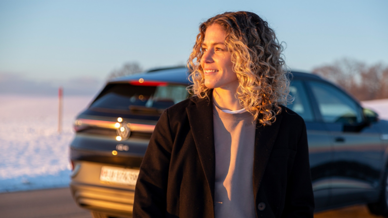 Luana Bühler im Fokus, während der ID.4 im Hintergrund steht