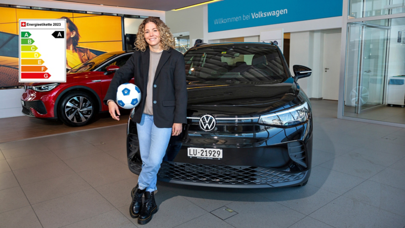 Luana Bühler lehnt sich mit einem Fussball in der Hand am ID.4 an