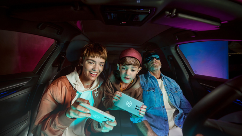 Father and two children in a Volkswagen. The children are playing with the AirConsole.