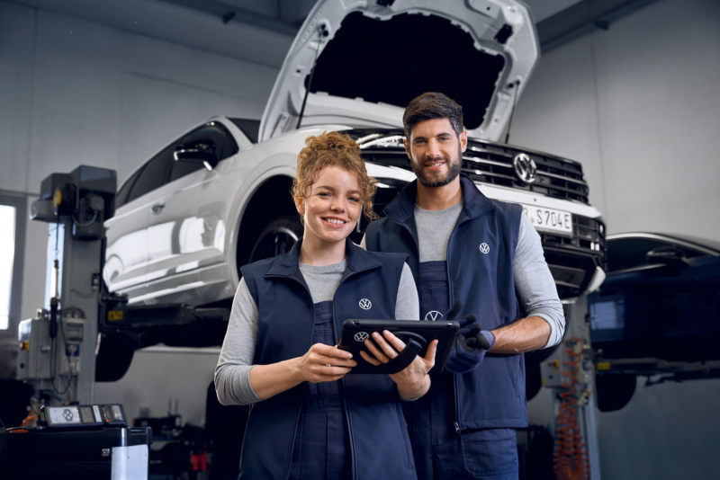 VW service employee and customer next to VW ID.3 looking at a tablet