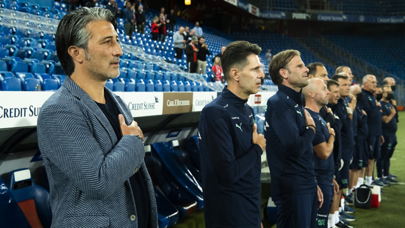 Murat Yakin si mette in fila con gli altri calciatori e canta l'inno nazionale.