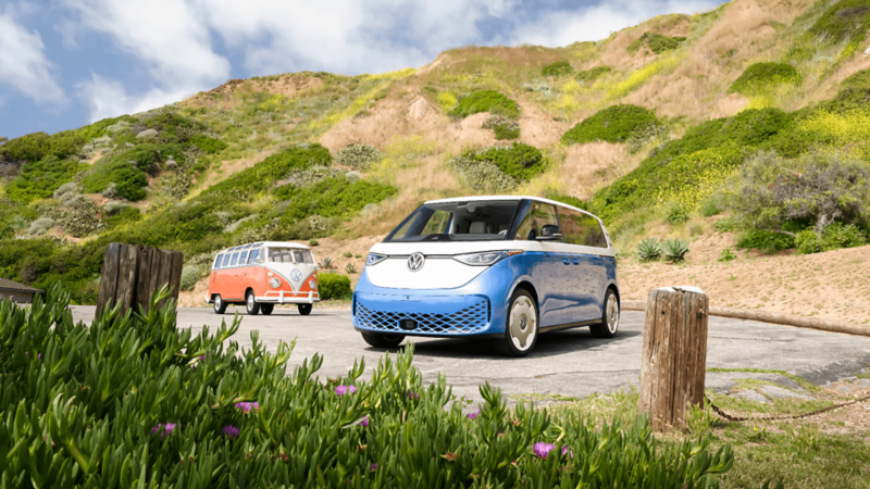 Un Volkswagen ID. Buzz 2025 bleu et blanc garé près d'une colline verdoyante.