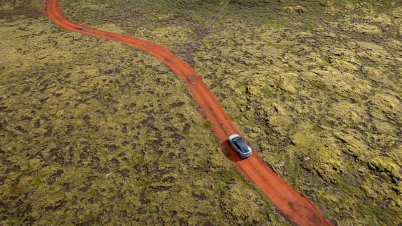 Una strada rosso fuoco attraversa un campo di lava ricoperto di muschio e in lungo e in largo non ci sono segni di civiltà.