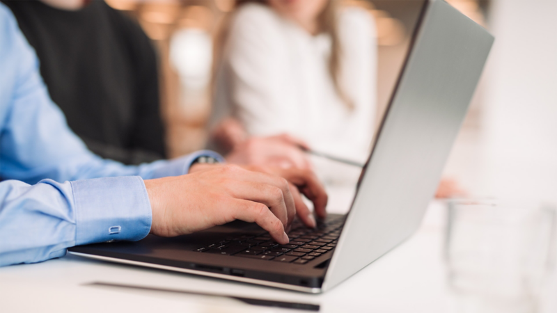 Two hands working at a laptop