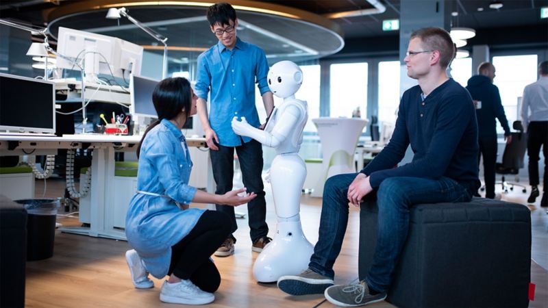 A woman and two men working on a humanoid robot