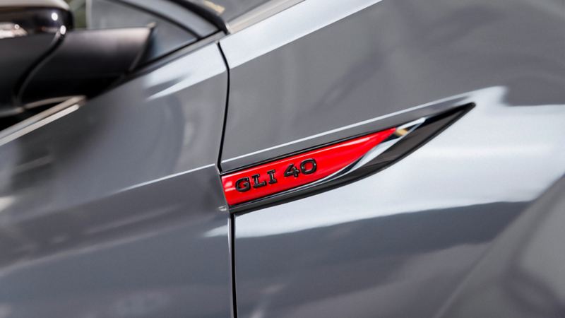 The rear end of the Jetta GLI 2024. The car is silver in color and the photo is focused on the red and black “GLI 40” badge on the car.