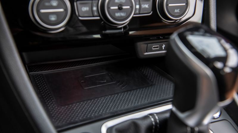 La Jetta 2024 de Volkswagen avec sa console centrale. La console dispose de trois bouches d’aération circulaires avec des ornements chromés. Sous les conduits d’aération, il y a une rangée de boutons pour la climatisation et le système d’infodivertissement de la voiture. La console dispose également d’un port USB et d’une prise de courant 12 V.
