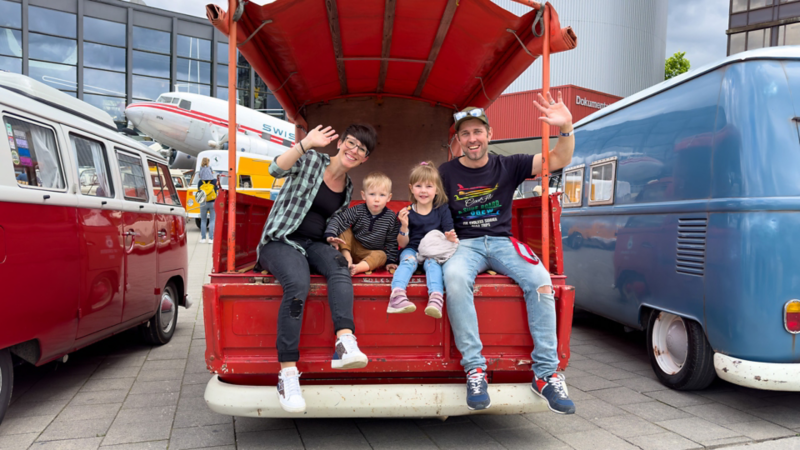 Eine Familie sitzt auf einem VW Bulli
