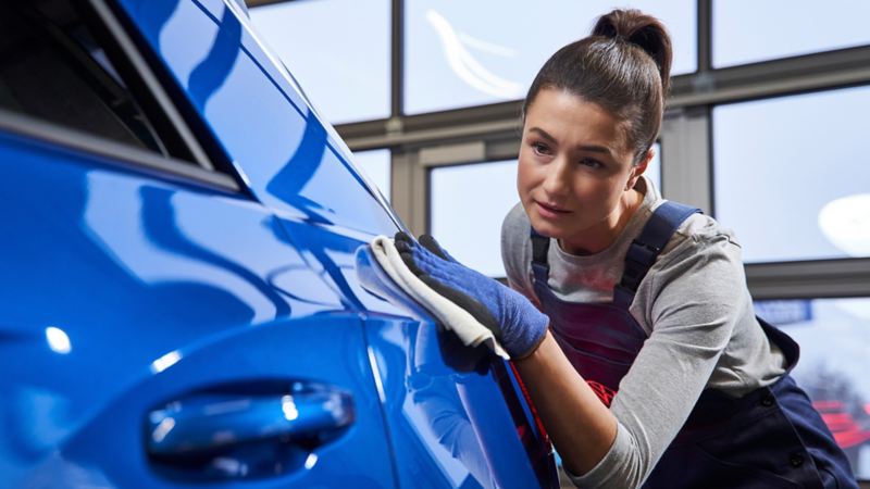 Frau poliert blauen Volkswagen
