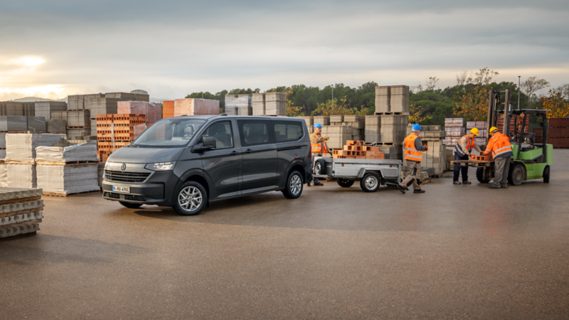 Tradespeople unload their material from a VW Transporter panel van.