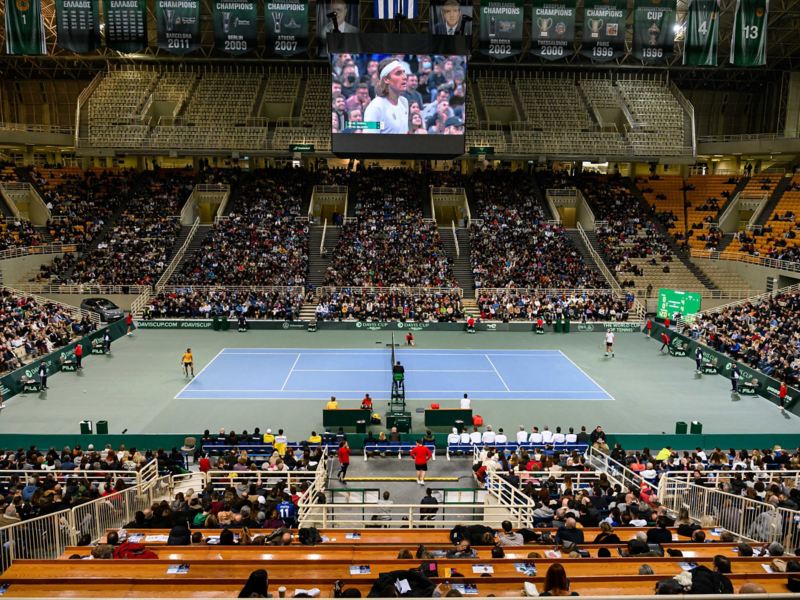 H Kosmocar-Volkswagen, Εθνικός Χορηγός της Ε.Φ.Ο.Α.- Γήπεδο τένις ΟΑΚΑ που στο βάθος σε οθόνη φαίνεται ο Τσιτσιπάς.