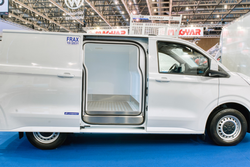 Vue de profil d'un véhicule vw Transporter utilitaire frigorifique blanc dont la porte latérale est ouverte, laissant entrevoir un espace de chargement avec un sol métallique.