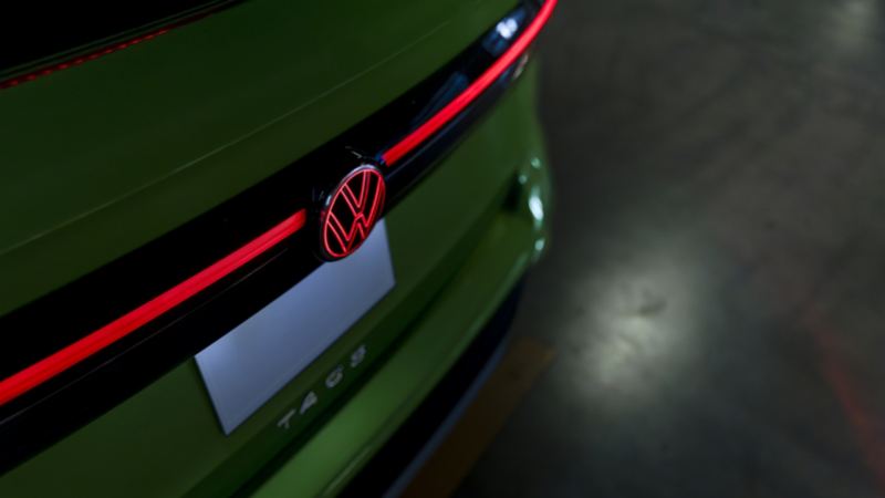 Gros plan sur le bandeau lumineux arrière à LED du Taos 2025 vert et son logo Volkswagen, mettant en valeur son design moderne.