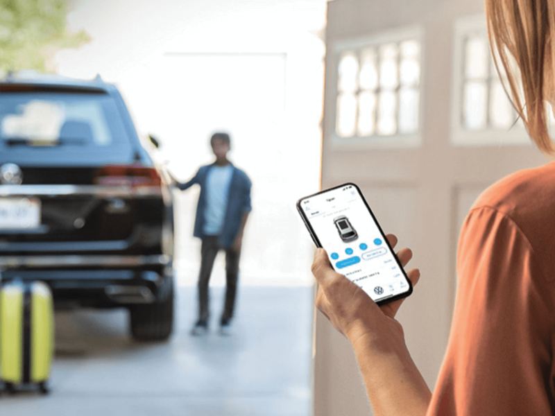 L’application Car-NetMD sur un téléphone avec un véhicule Volkswagen en arrière-plan