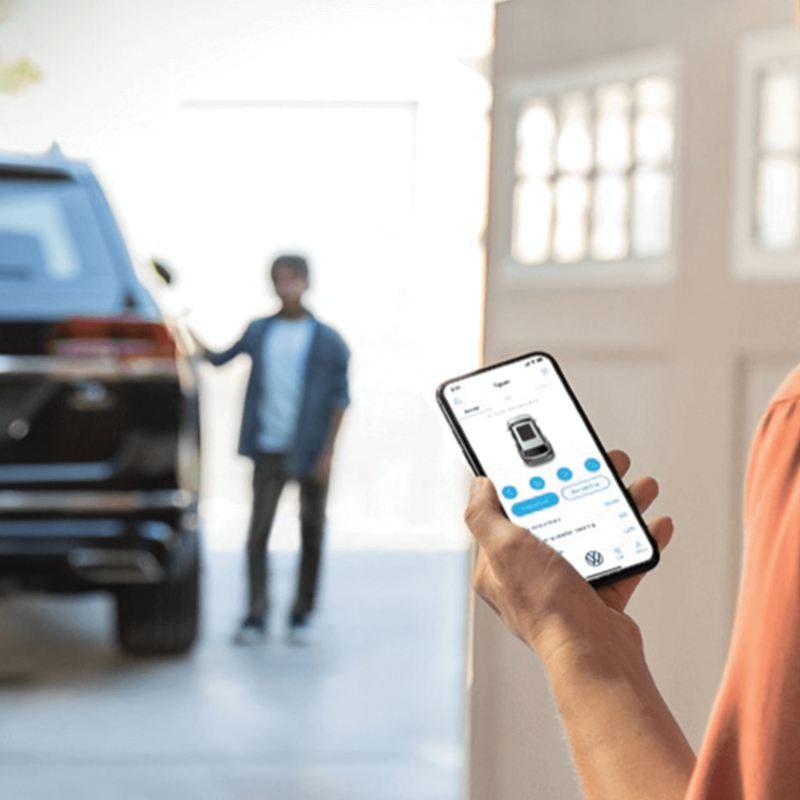 L’application Car-NetMD sur un téléphone avec un véhicule Volkswagen en arrière-plan