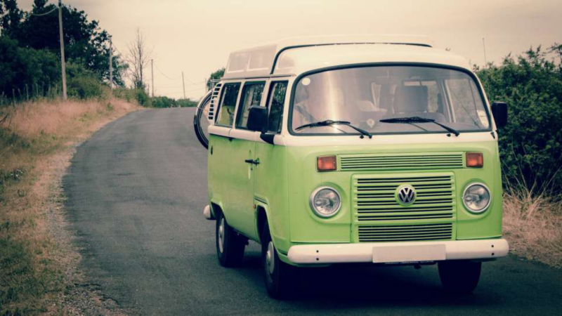 A vintage VW campervan driving down a road
