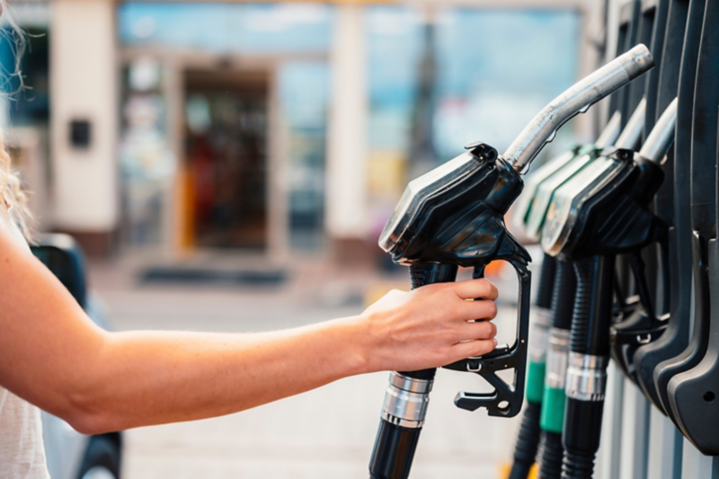 Closeup of woman pumping gasoline fuel in car at gas station.