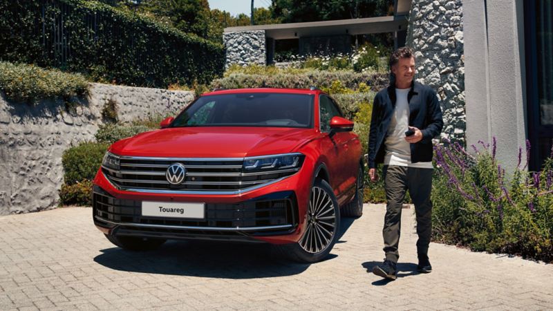The new 2024 VW Touareg being parked at a house, a man walks in front of it.