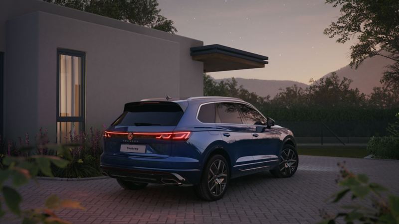 The new VW Touareg parked in front of a house at night, the rear tail light is illuminated
