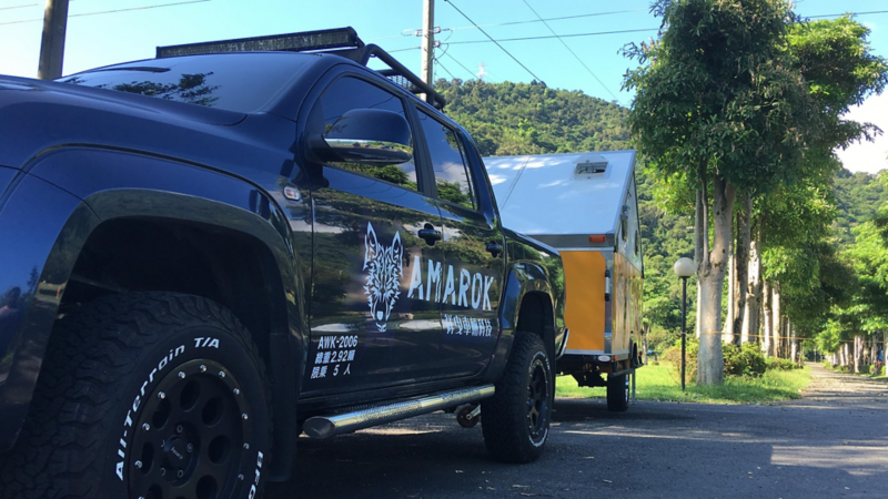 珍珠黑色Amarok拖著越野型露營拖車，停在山邊小路上
