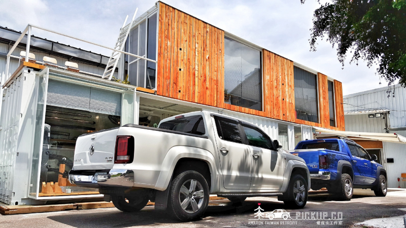兩台Amarok停在貨櫃改建的商店前，前景是香草白色Amarok、遠景是水藍色Amarok